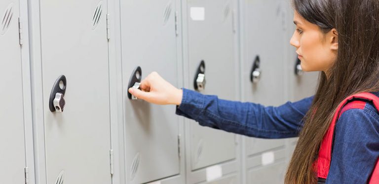 Unsmiling student opening her locker at university